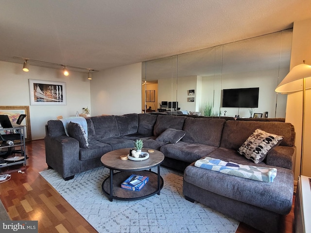 living room featuring wood-type flooring, track lighting, and a textured ceiling