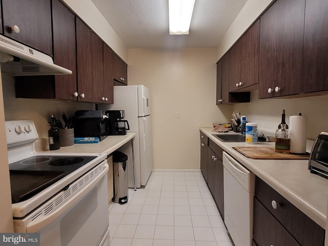 kitchen with white appliances, light tile patterned flooring, a textured ceiling, dark brown cabinetry, and sink