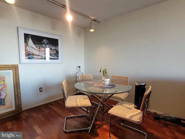 dining area with dark hardwood / wood-style flooring and track lighting