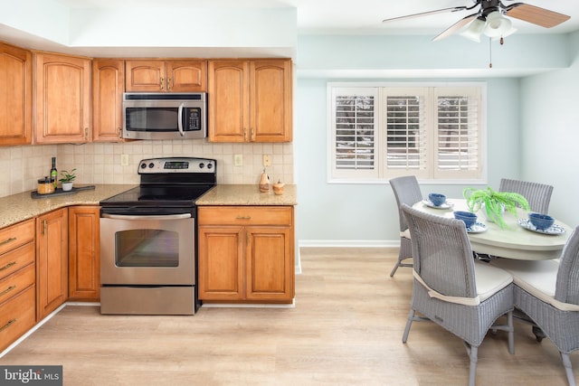 kitchen featuring ceiling fan, light wood-type flooring, decorative backsplash, and stainless steel appliances