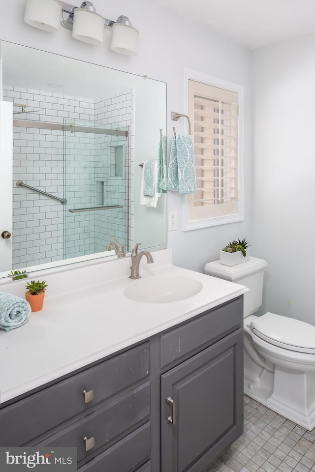 bathroom featuring a shower with door, toilet, vanity, and tile patterned flooring