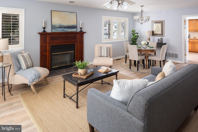 living room featuring light wood-type flooring and ceiling fan with notable chandelier