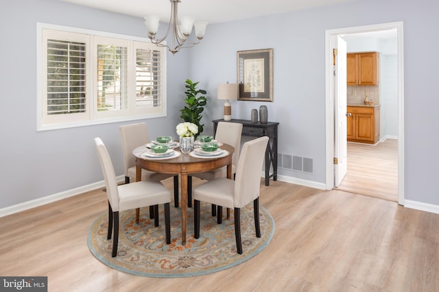 dining space with an inviting chandelier and light hardwood / wood-style flooring