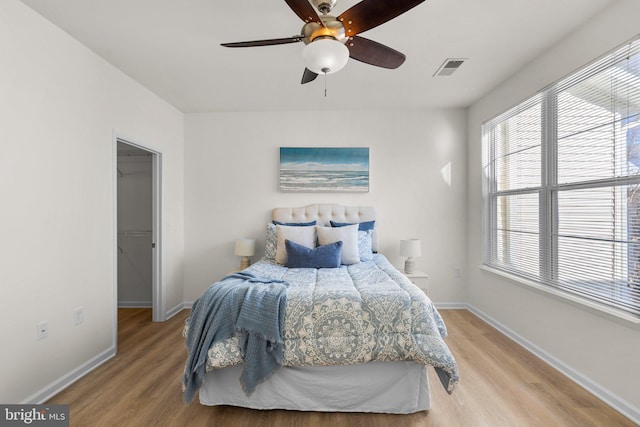 bedroom with a walk in closet, ceiling fan, a closet, and hardwood / wood-style flooring