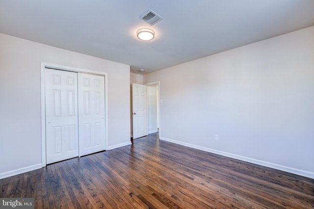 unfurnished bedroom with a closet and dark hardwood / wood-style flooring