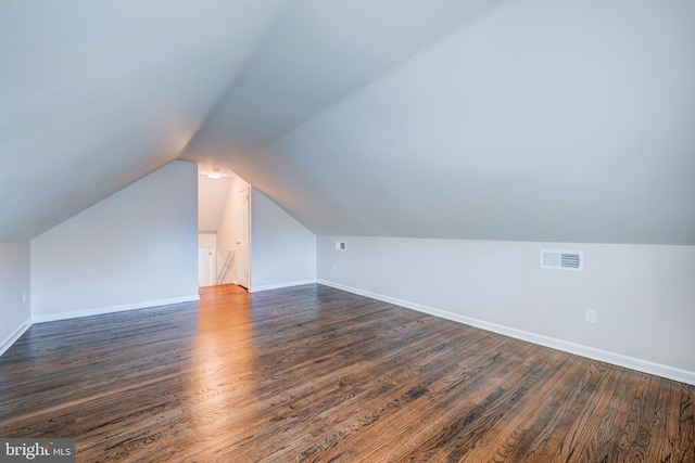 additional living space featuring dark wood-type flooring and vaulted ceiling