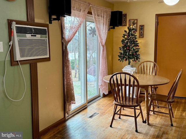 dining space featuring hardwood / wood-style floors and an AC wall unit