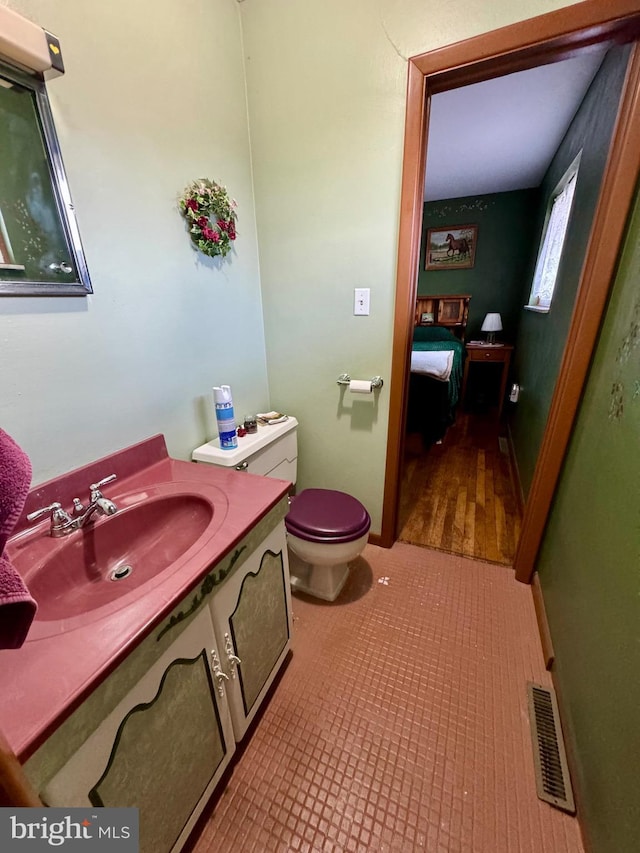 bathroom with toilet, vanity, and tile patterned flooring