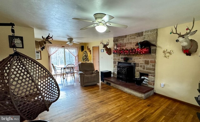 living room featuring hardwood / wood-style flooring, a wood stove, and ceiling fan