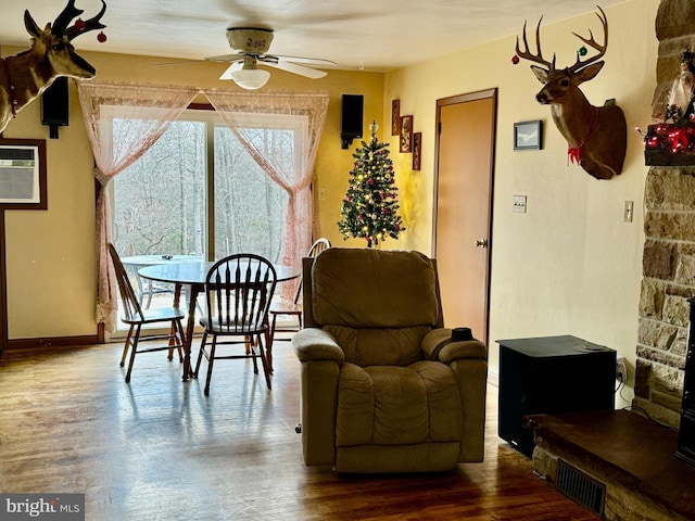 dining space with ceiling fan, wood-type flooring, and a wall mounted air conditioner