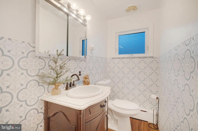 bathroom with hardwood / wood-style floors, vanity, a baseboard radiator, and toilet