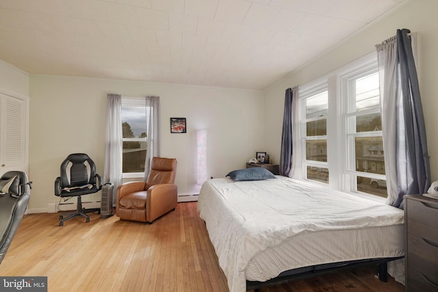 bedroom with hardwood / wood-style flooring and a baseboard heating unit