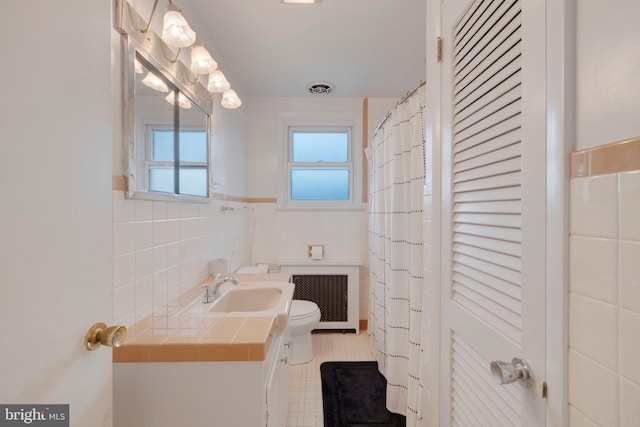 bathroom featuring a wealth of natural light, vanity, toilet, and radiator