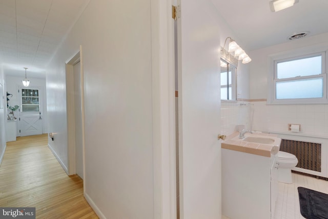 bathroom with hardwood / wood-style floors, vanity, toilet, tile walls, and radiator heating unit