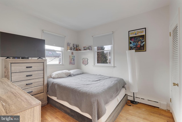 bedroom with light wood-type flooring and baseboard heating