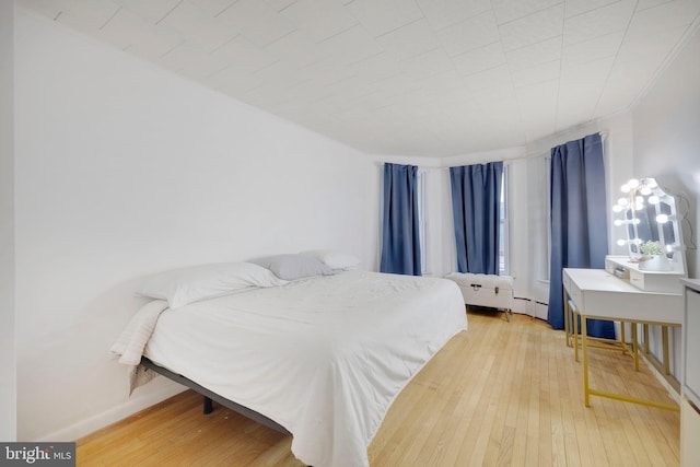 bedroom featuring hardwood / wood-style floors and a baseboard heating unit