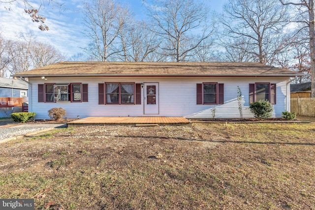 single story home with a wooden deck and a front lawn