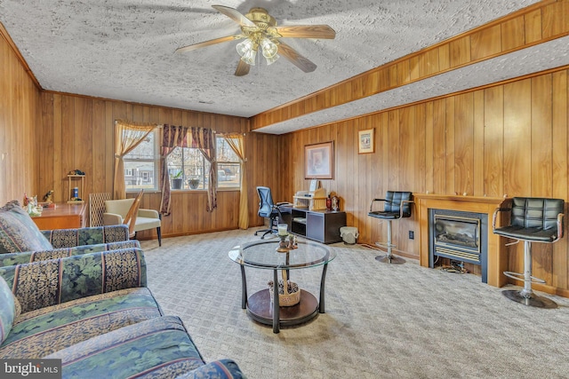 living room featuring light carpet, wooden walls, ceiling fan, and a textured ceiling