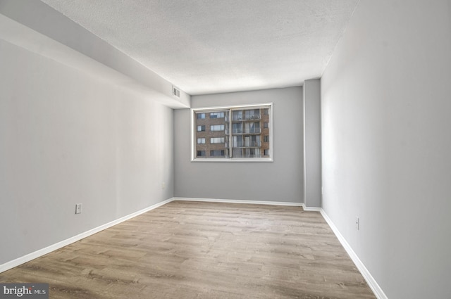 empty room featuring a textured ceiling and light hardwood / wood-style flooring