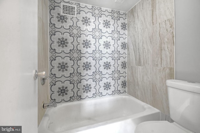 bathroom featuring toilet and tiled shower / bath combo