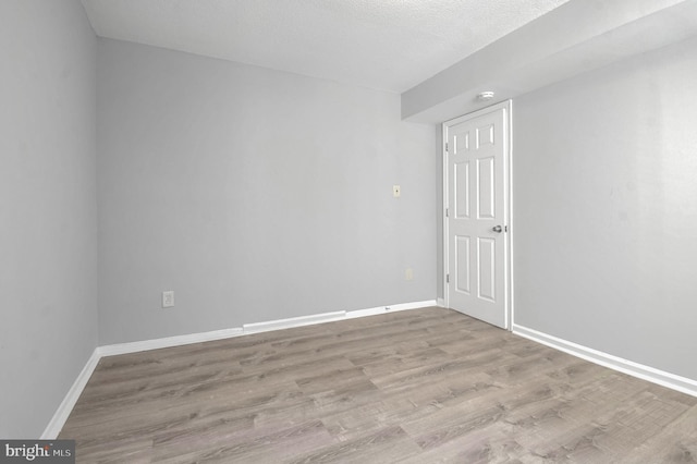 empty room with light hardwood / wood-style floors and a textured ceiling