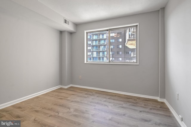 spare room with a textured ceiling and light wood-type flooring