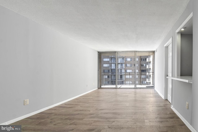 spare room with hardwood / wood-style flooring, floor to ceiling windows, and a textured ceiling