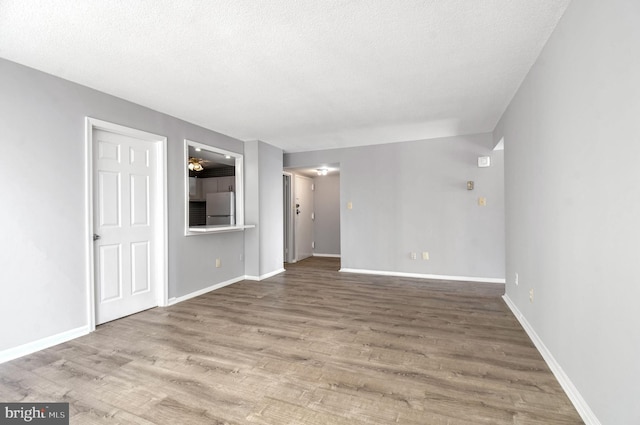 unfurnished living room featuring hardwood / wood-style flooring and a textured ceiling