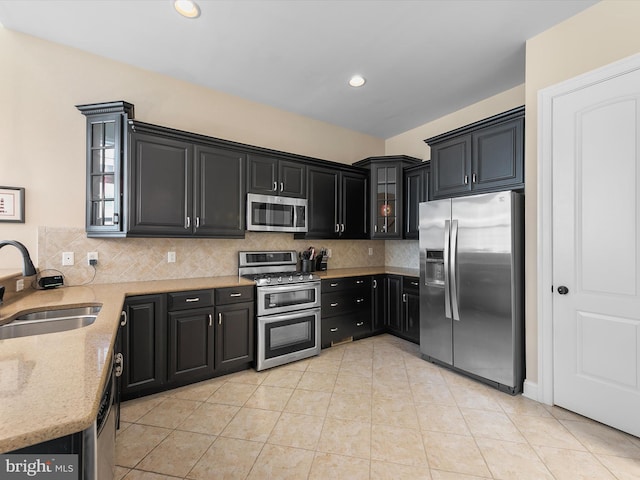 kitchen featuring sink, decorative backsplash, light stone countertops, light tile patterned floors, and stainless steel appliances