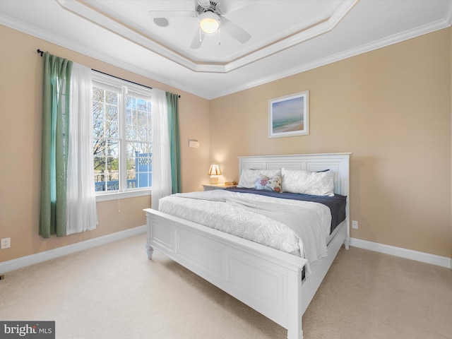 carpeted bedroom with a raised ceiling, ceiling fan, and crown molding