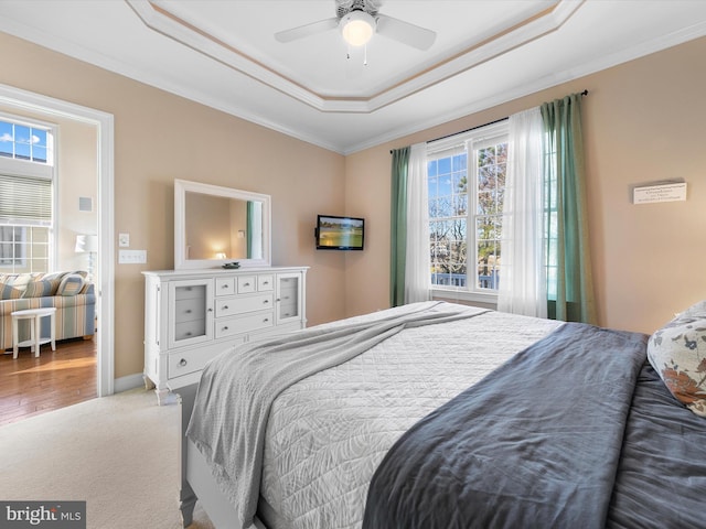 bedroom with a raised ceiling, ceiling fan, crown molding, and carpet floors