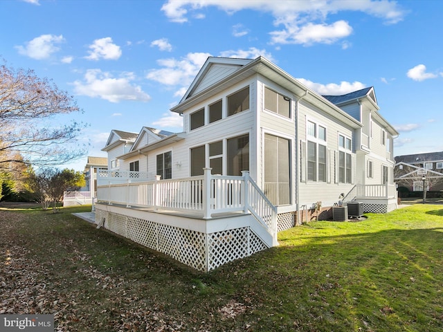 rear view of house with a yard, a deck, and cooling unit