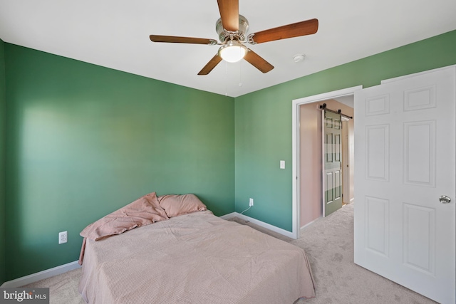 carpeted bedroom featuring a barn door and ceiling fan