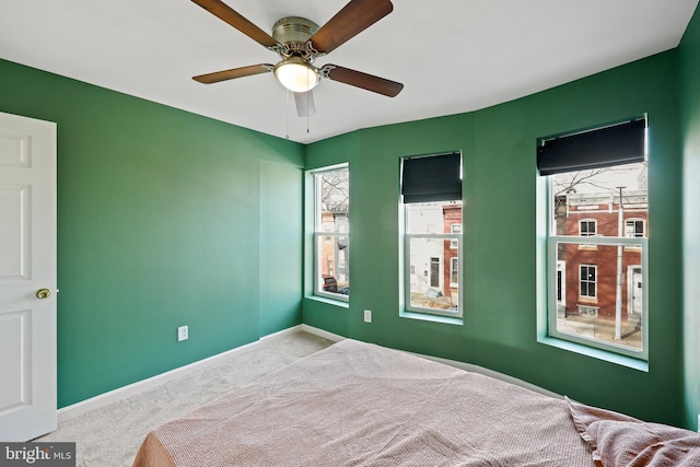 carpeted bedroom with multiple windows and ceiling fan