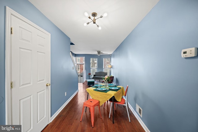 dining space with dark wood-type flooring and ceiling fan with notable chandelier