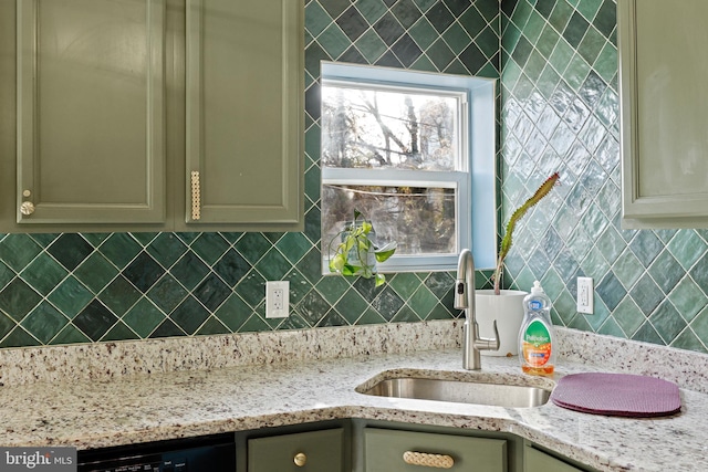 kitchen with cream cabinets, light stone counters, sink, and black dishwasher