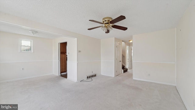 carpeted spare room with a textured ceiling and ceiling fan