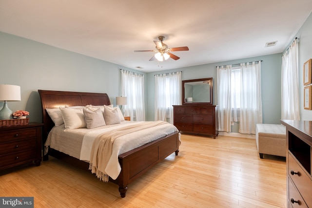 bedroom with ceiling fan, light hardwood / wood-style floors, and multiple windows