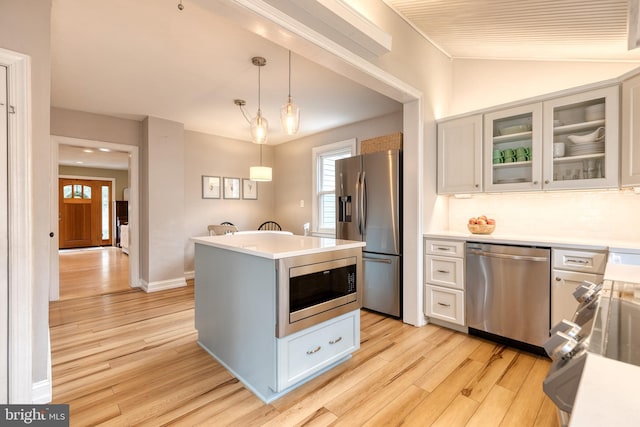 kitchen featuring decorative backsplash, white cabinetry, hanging light fixtures, and appliances with stainless steel finishes