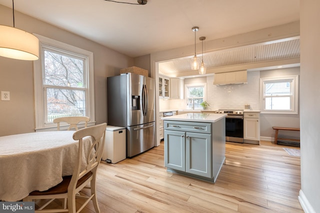 kitchen featuring stainless steel appliances, white cabinetry, and hanging light fixtures