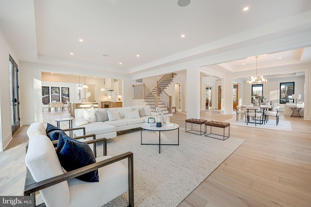 living room with a raised ceiling, light wood-type flooring, and a chandelier