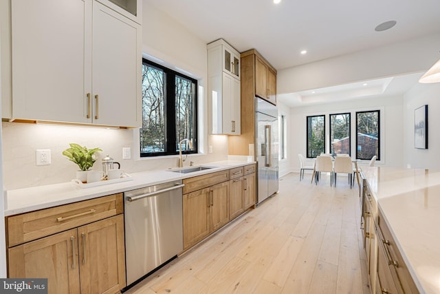 kitchen featuring stainless steel appliances, white cabinets, sink, and light hardwood / wood-style floors