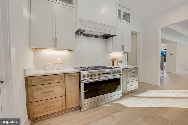 kitchen with light hardwood / wood-style floors, range with two ovens, light brown cabinetry, white cabinets, and tasteful backsplash