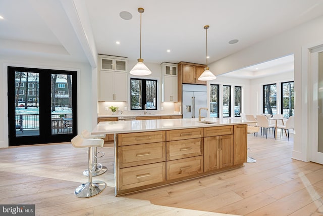 kitchen with stainless steel built in fridge, a kitchen breakfast bar, and a large island with sink