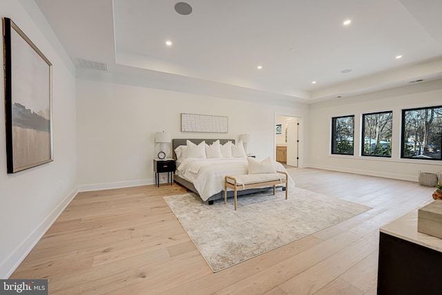 bedroom featuring light wood-type flooring and a tray ceiling