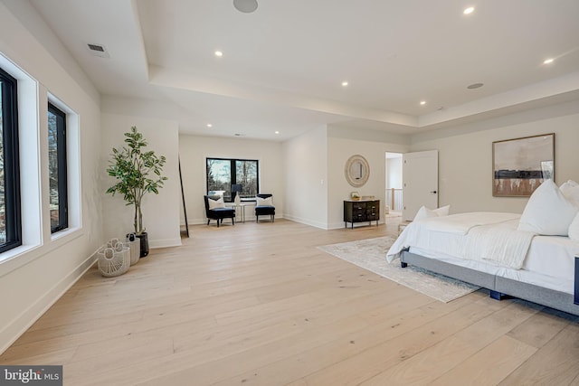 bedroom featuring a raised ceiling and light hardwood / wood-style flooring