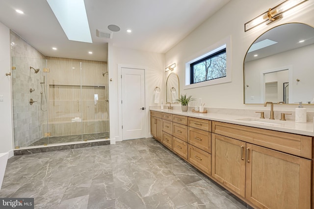 bathroom with a shower with door, a skylight, and vanity