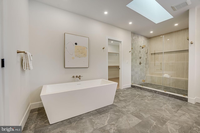 bathroom featuring a skylight and separate shower and tub