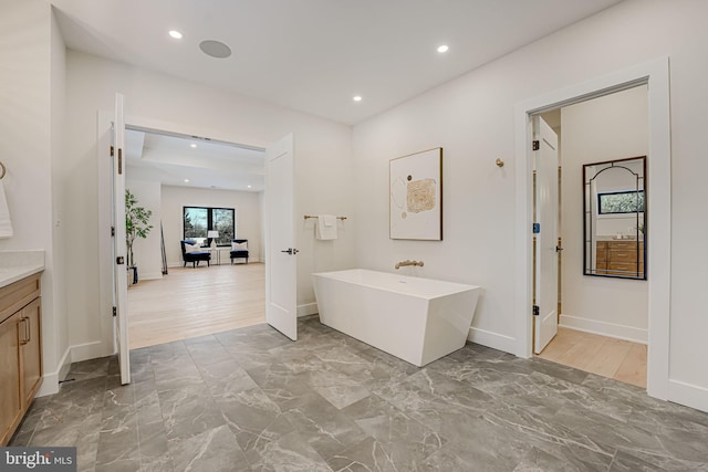 bathroom with hardwood / wood-style flooring, vanity, and a bathing tub