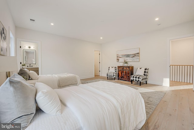 bedroom with light hardwood / wood-style floors and connected bathroom